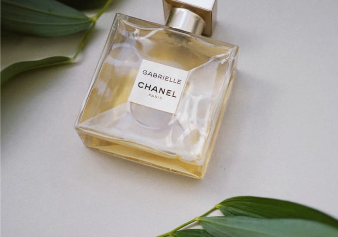 square
						bottle of
						perfume laying on an off-white surface